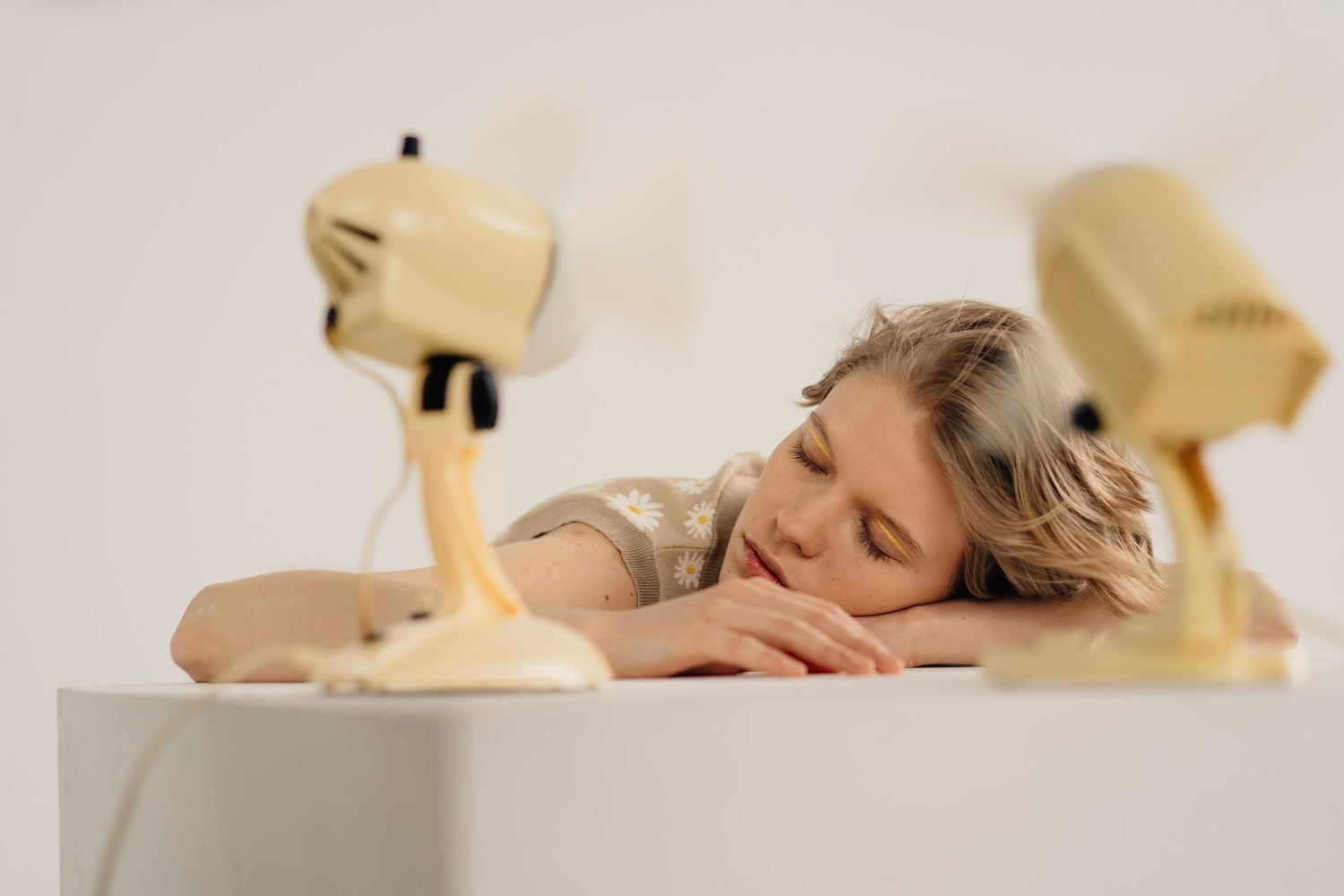 A calm scene of a woman resting with vintage fans in a minimalist setting, conveying tranquility.